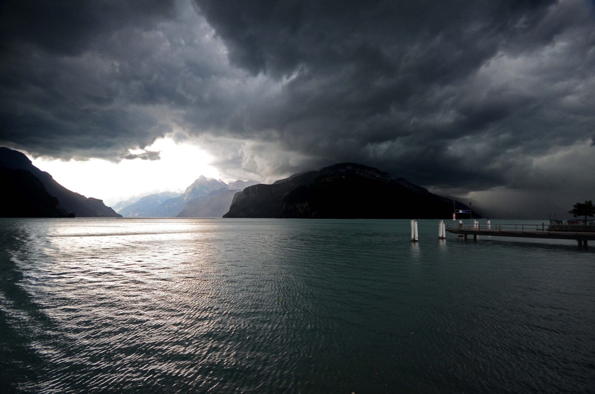 Der Urnersee bei Regenwolken auf der linken Seite sieht man die Sonnedurchscheinen