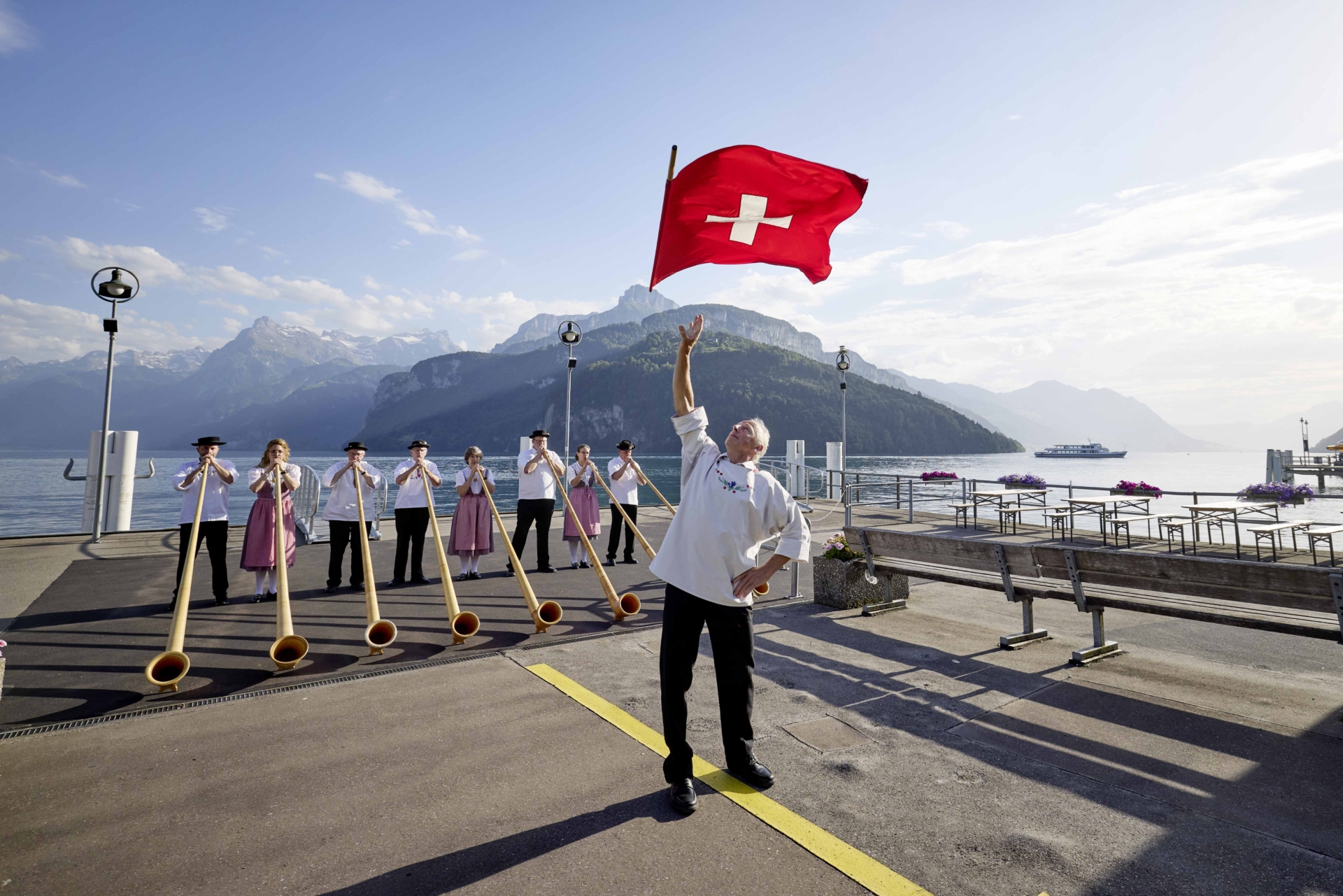 Traditioneller Alphorn- und Fahnenschwinger-Auftritt an der Schiffstation Brunnen in der Erlebnisregion Mythen mit Blick auf den Vierwaldstättersee und die Bergwelt.