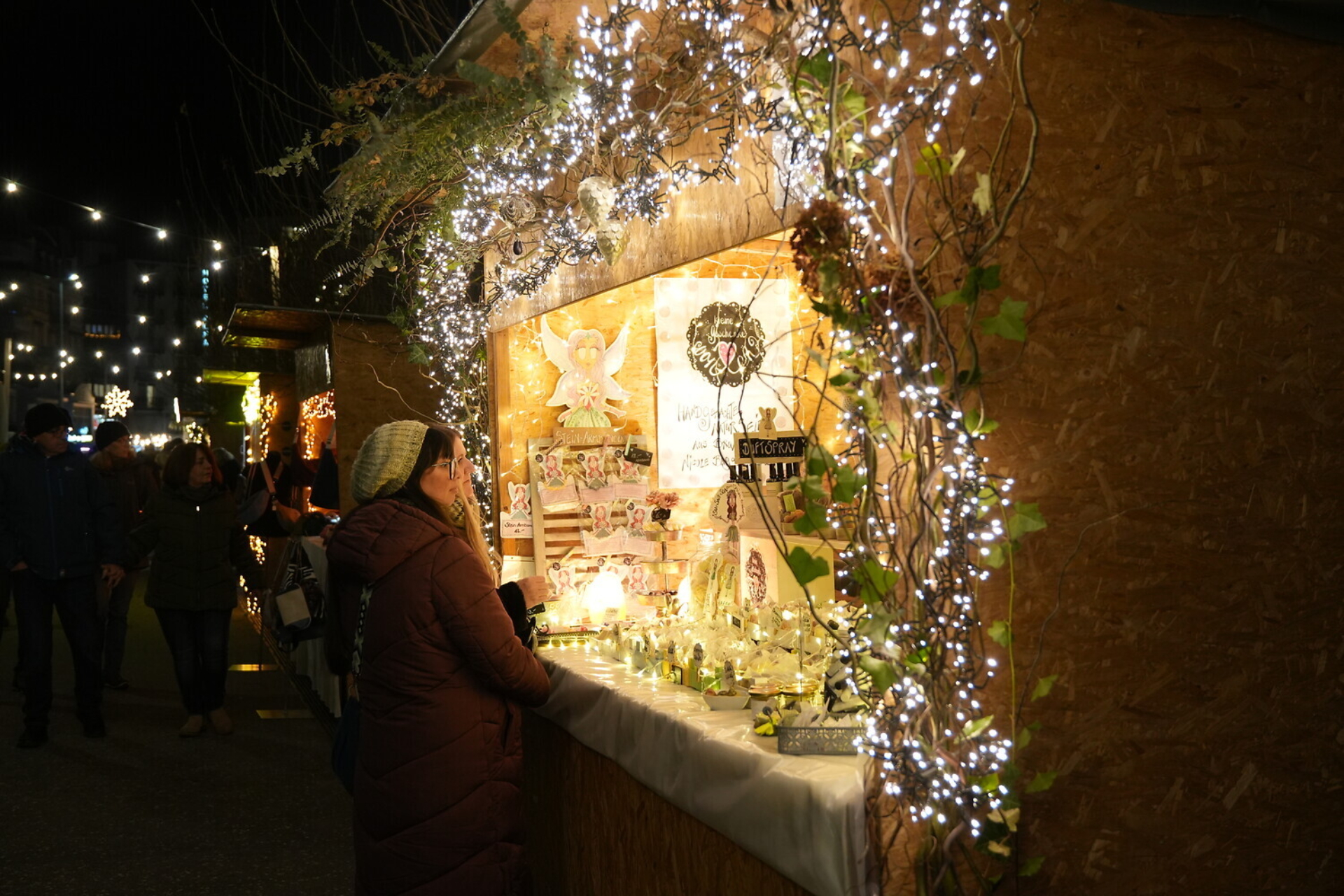 Weihnachtsmarkt am See in Brunnen. Zwei Damen stehen vor einem schöne dekorierten und beleuchteten Holzmarktstand.