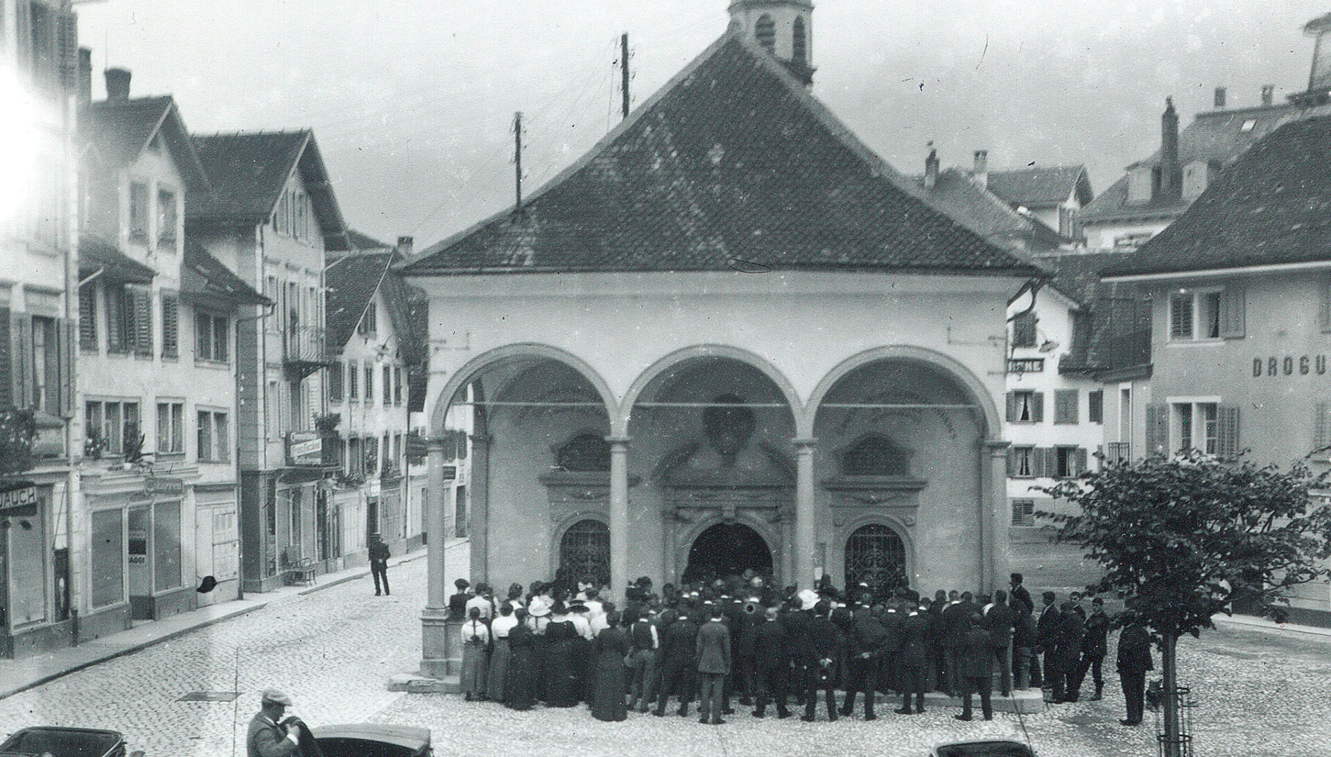 ein historisches Foto der Bundeskapelle in Brunnen in schwarz und weiss davor viele Menschen