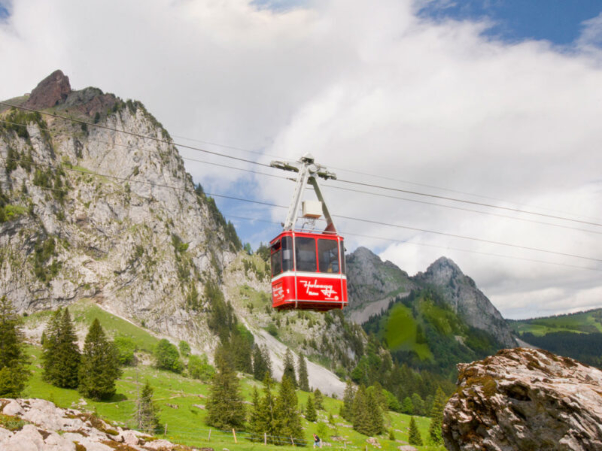 Die rote Kabine der Luftseilbahn Brunni - Holzegg fährt am grossen Mythen vorbei. Sommerliche Stimmung.