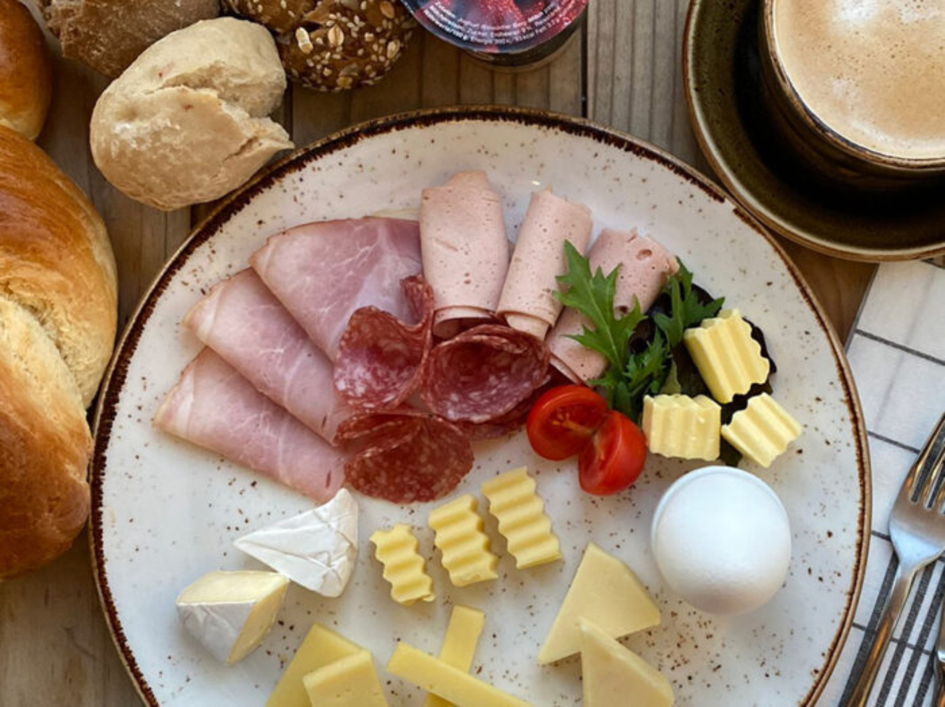 Chääsi Zmorgä in der Milchmanufaktur Einsiedeln. Ein grosser Zmorge-Teller mit Fleisch und Käse. Umringt von Zopf, Brot und Kaffee.