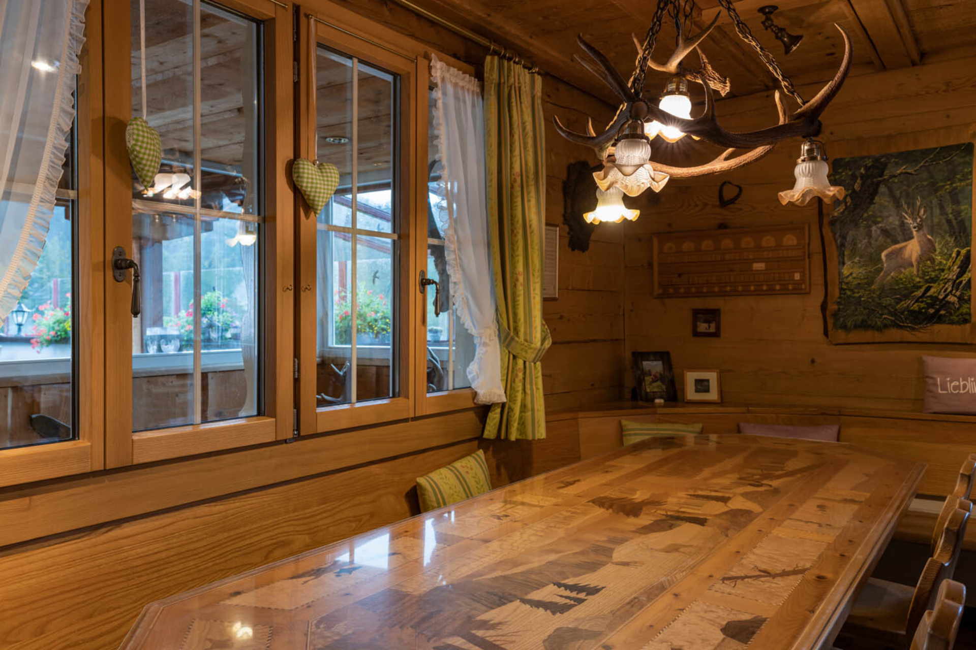 Grosser Holztisch im Restaurant Herrenboden. Über dem Tisch hängt eine Lampe mit Hirsch Geweih.