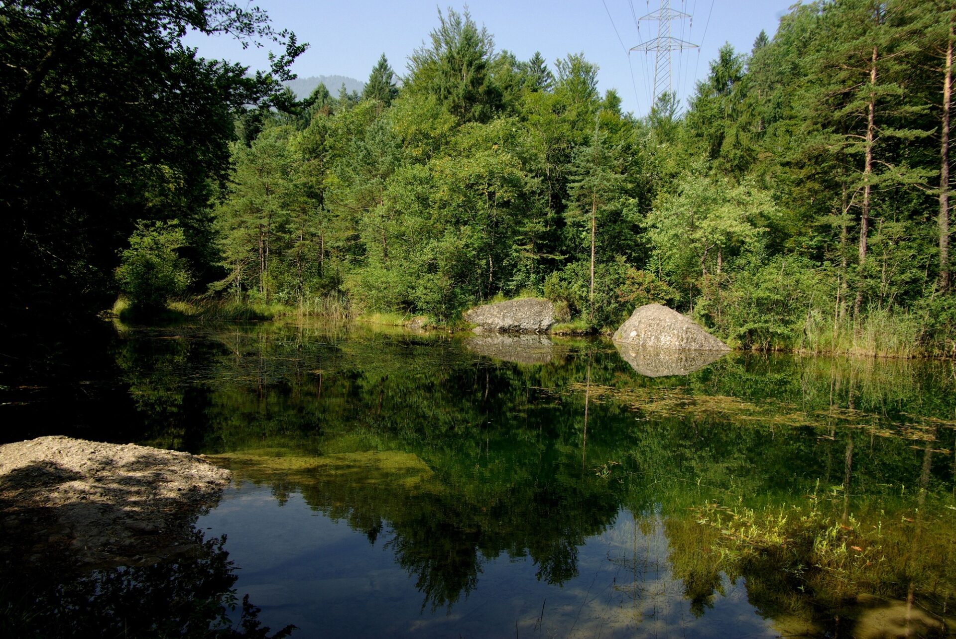 Spiegelglatter kleiner See umgeben von Wald.