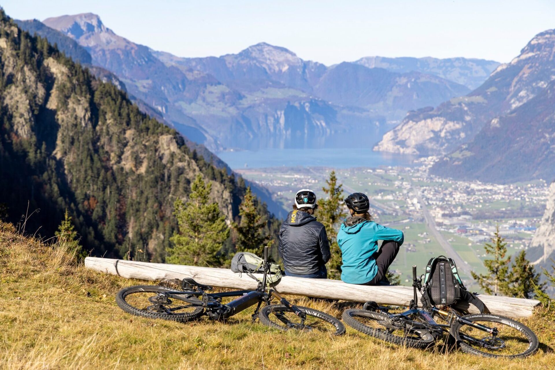 Zwei Personen geniessen eine Pause auf der Arnie Bike-Tour und die Aussicht auf die Urner Bergwelt sowie den Urnersee. Ihre Bikes sind hinter ihnen platziert.