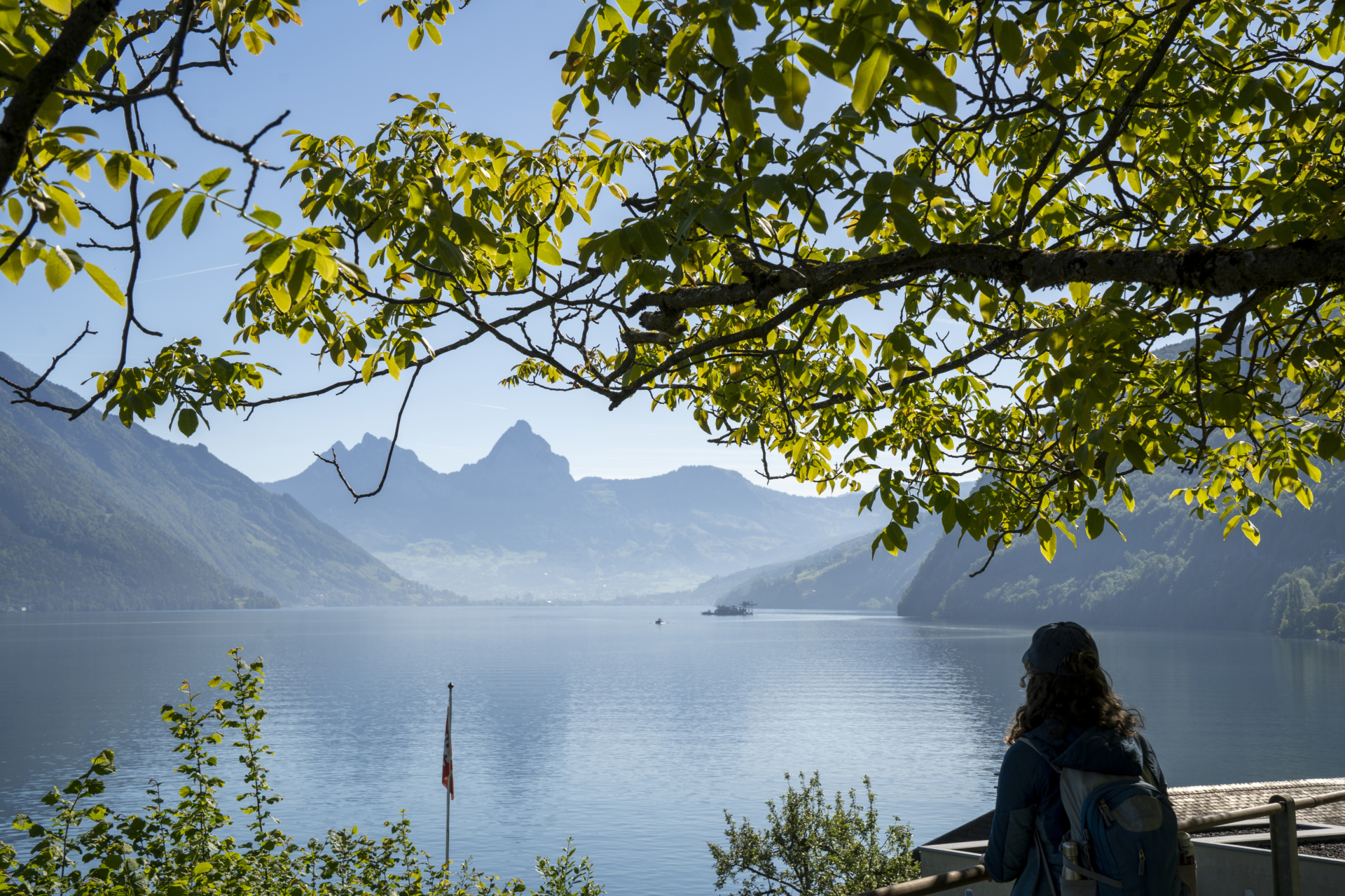 Eine Frau blickt von Beckenried auf den Vierwaldstättersee. Im Hintergrund sind die Mythen zu sehen. Sie befindet sich auf der siebten Etappe des Waldstätterwegs.